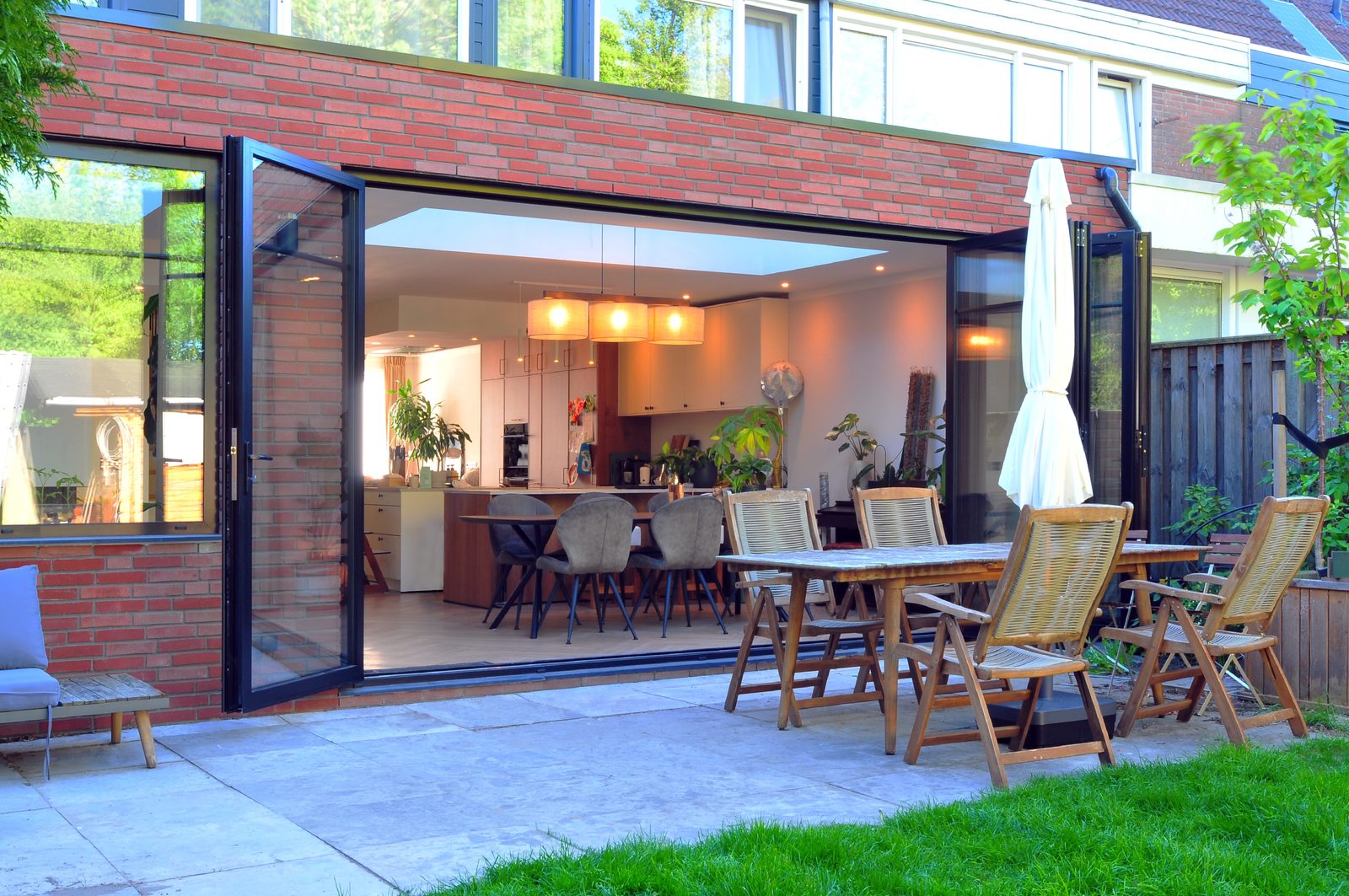 Uitbouw met open schuifpui en eettafel in de tuin, gerealiseerd door HR Huis Renovatie in Dordrecht